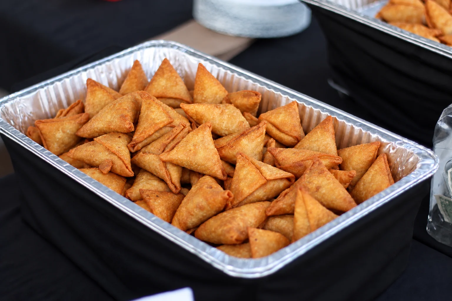 A tray filled with golden, crispy samosas